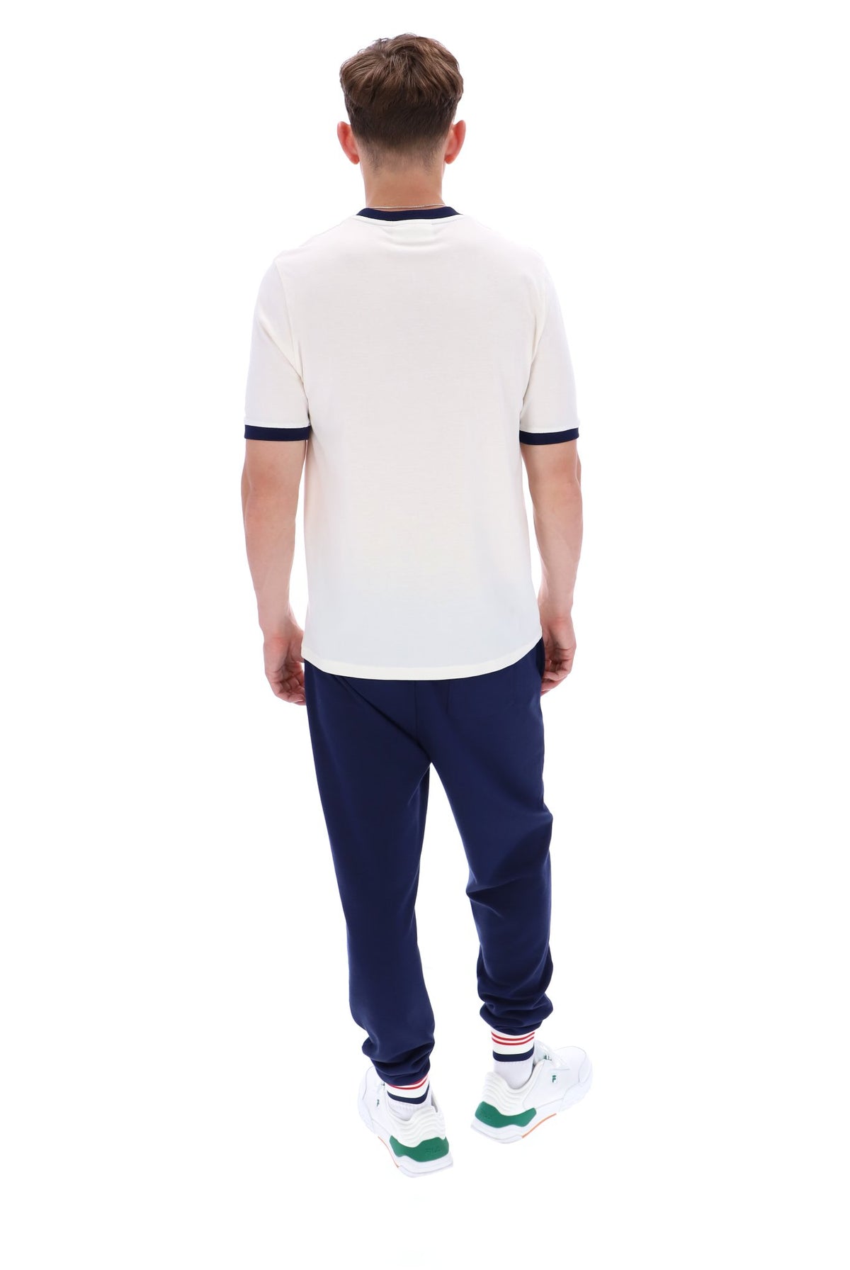 A male model wearing a white and navy ringer t-shirt and navy bottoms on a white background