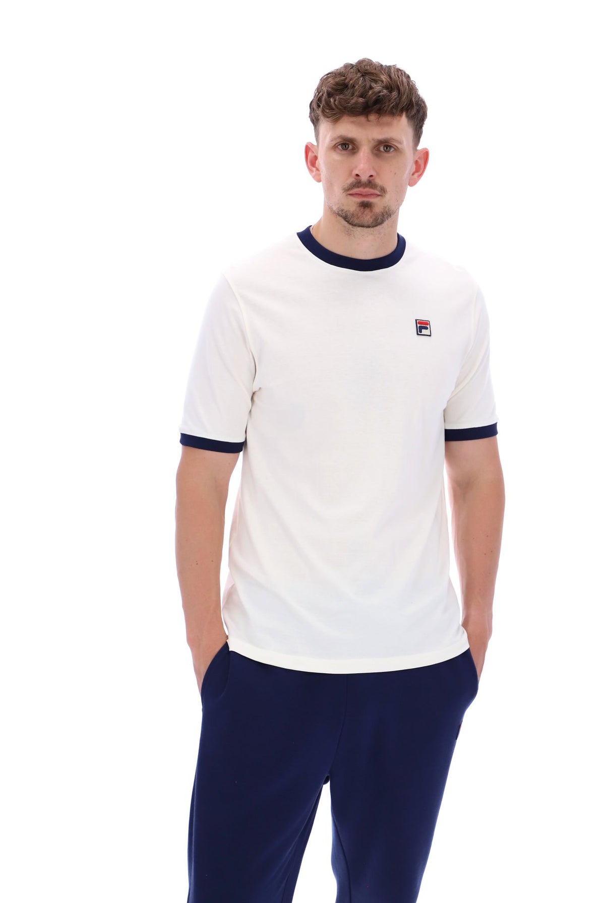A male model wearing a white and navy ringer t-shirt with the FILA logo on the chest.