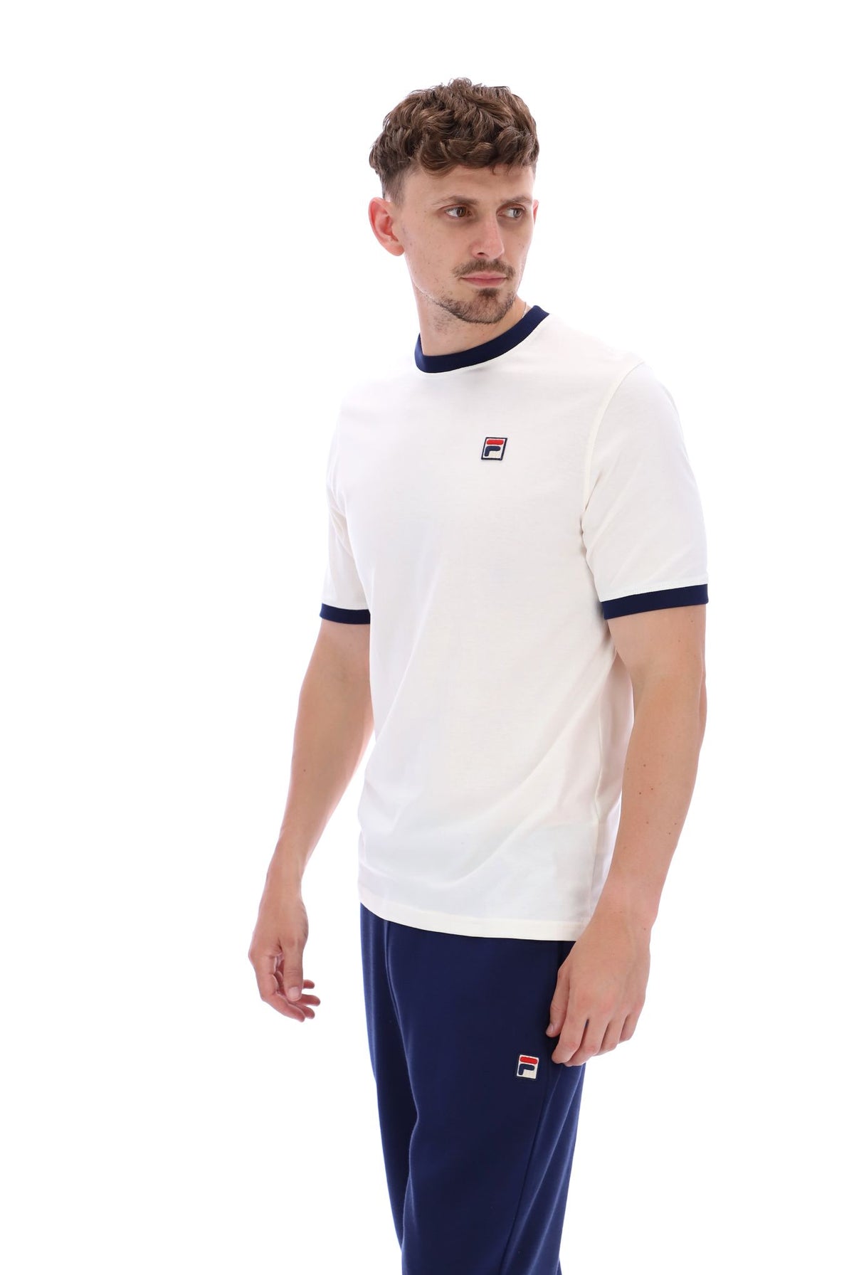 A male model wearing a white and navy ringer t-shirt with the FILA logo on the chest.