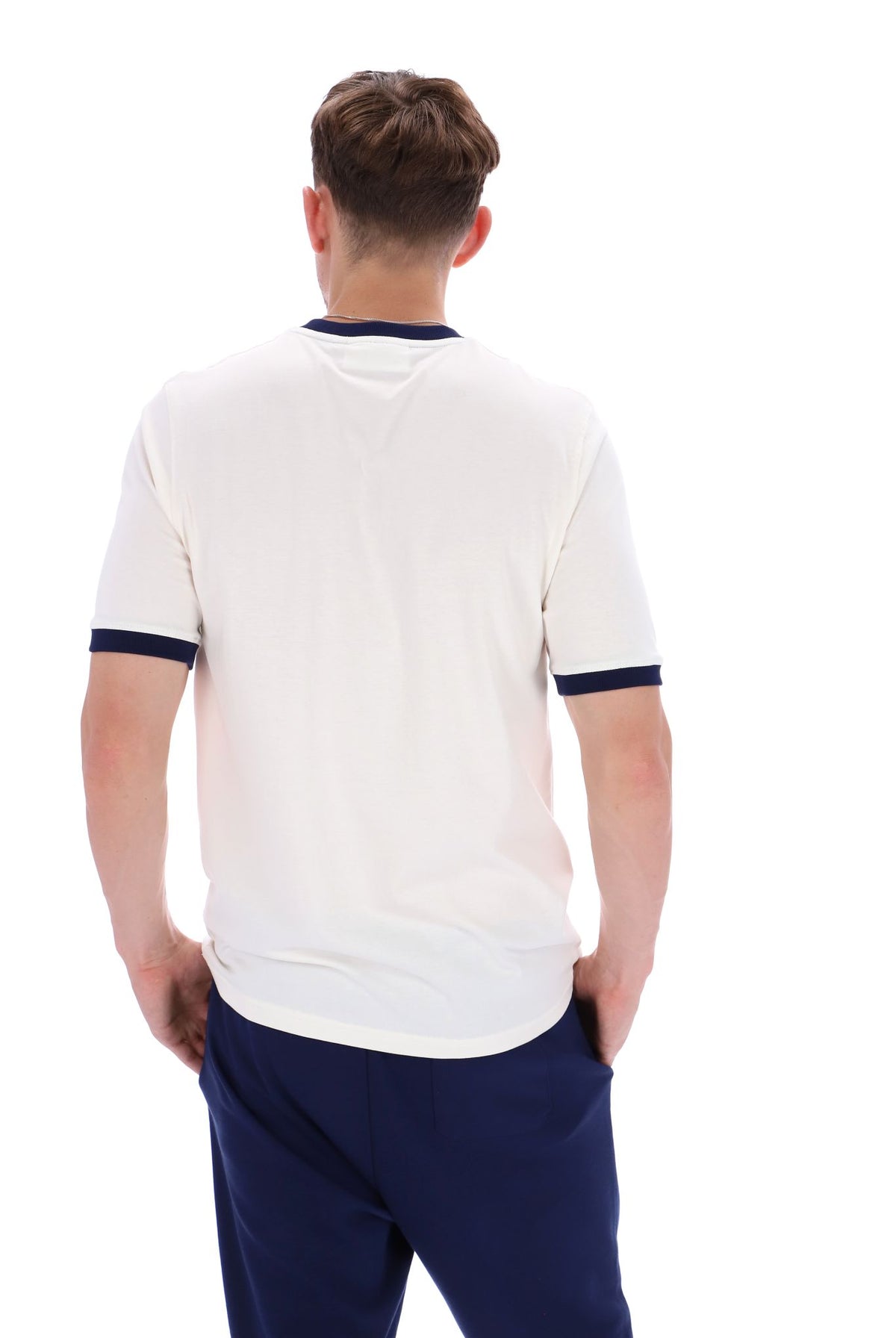 A male model wearing a white and navy ringer t-shirt with navy joggers on a white background