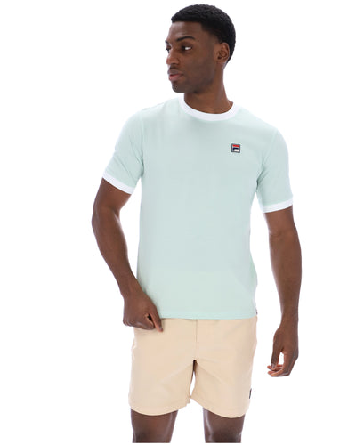Man wearing a light green t-shirt with a small logo on a white background