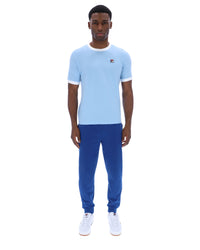 Man wearing a light blue t-shirt and blue pants on a white background
