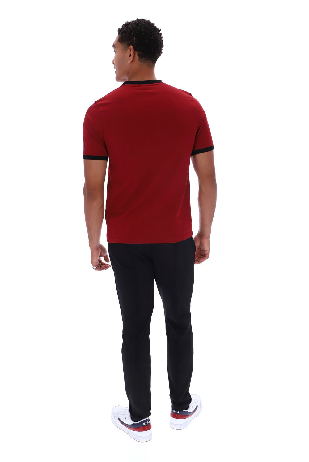 A man viewed from the back wearing a red short-sleeve t-shirt with black trim, black pants, and white sneakers, set against a plain white background.