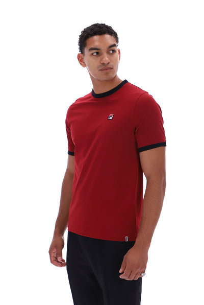 A man wearing a red short-sleeve t-shirt with black trim on the collar and sleeve cuffs, featuring a small white and red logo on the left chest, set against a plain white background.