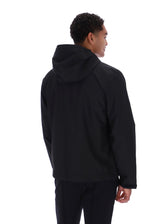A man shown from the back wearing a black hooded jacket and black pants against a plain white studio background.