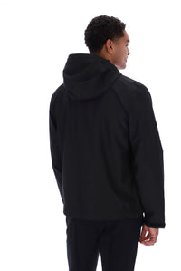 A man shown from the back wearing a black hooded jacket and black pants against a plain white studio background.