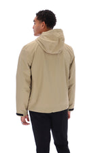 A man shown from the back wearing a light beige hooded jacket and black pants, photographed against a plain white studio background.