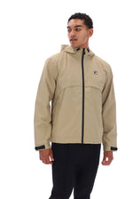 A man wearing a beige hooded windbreaker jacket with black trim and a small Fila logo on the chest, paired with black pants, photographed against a plain white background.