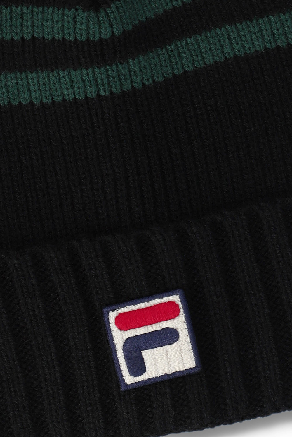 Close-up of a black ribbed knit beanie with dark green horizontal stripes near the top and a white embroidered Fila logo patch on the cuff.