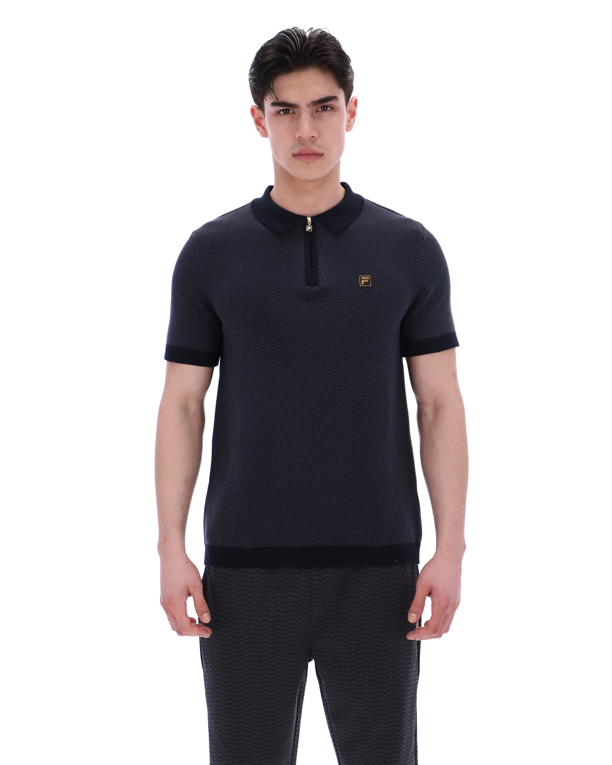 Man wearing a dark blue polo shirt with a small logo on a white background