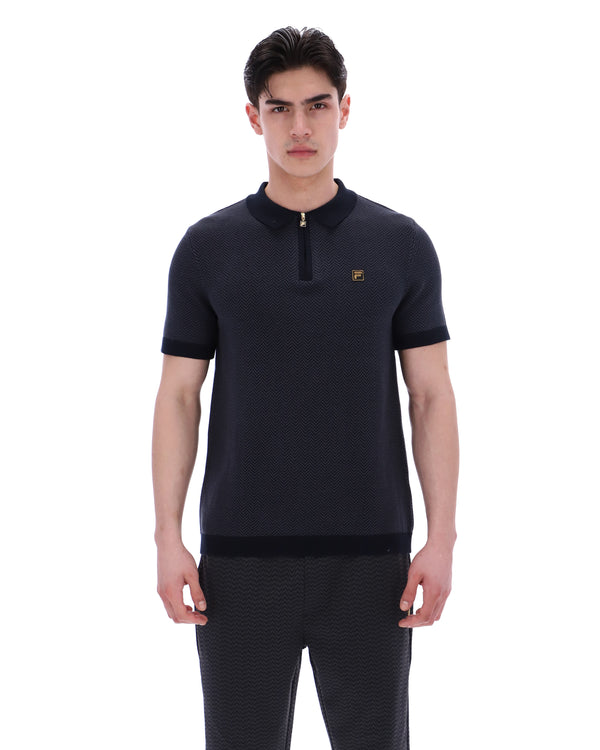 Man wearing a dark blue polo shirt with a small logo on a white background