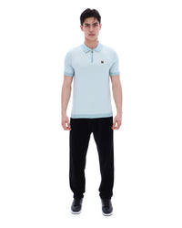Man wearing a light blue polo shirt and black pants on a white background