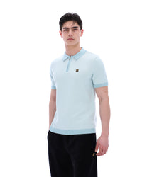 Man wearing a light blue polo shirt with a brand logo on a white background