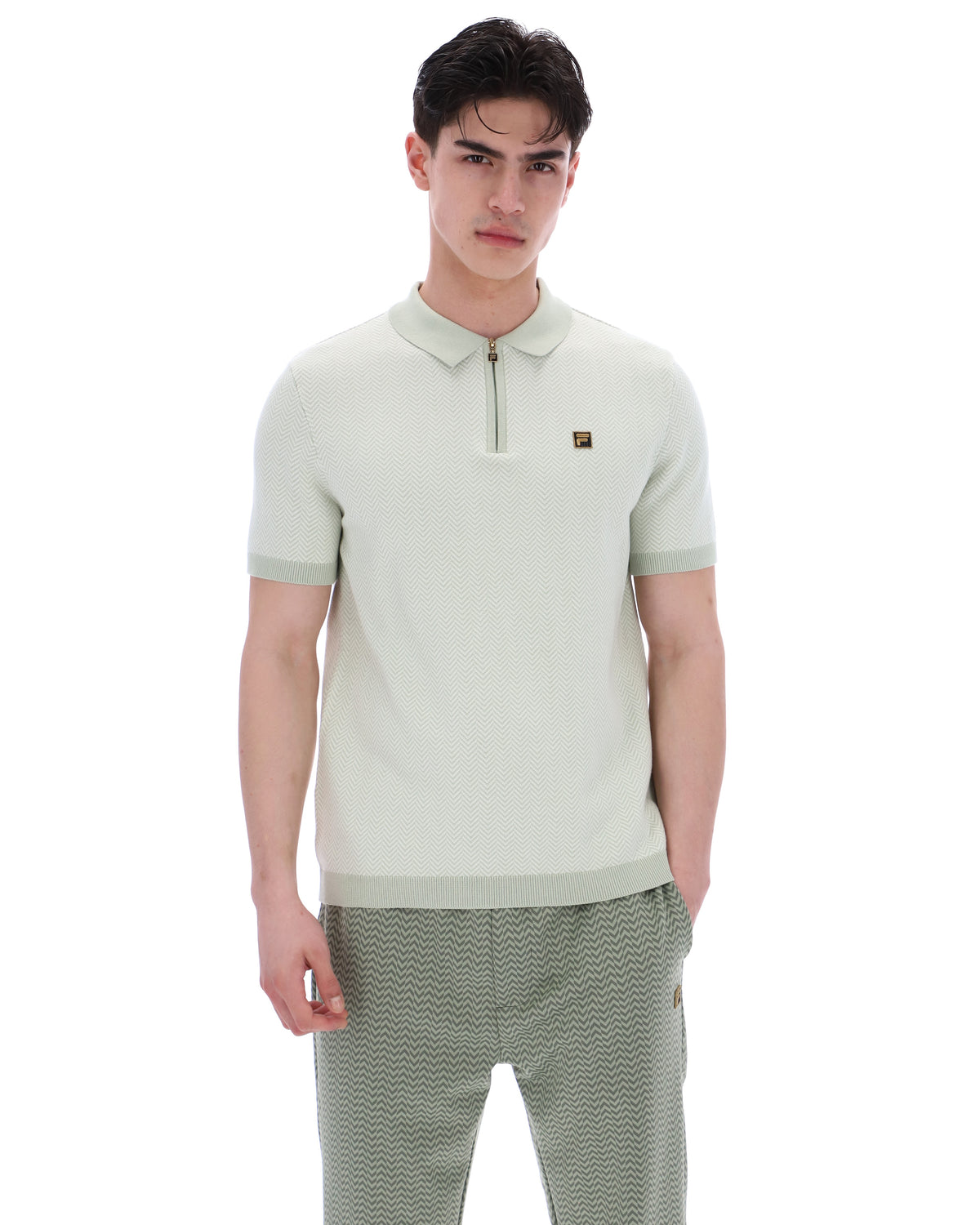 Man wearing a light green polo shirt with a small logo on a white background
