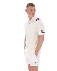 Man wearing a white polo shirt with a FILA logo on the sleeve, on a white background