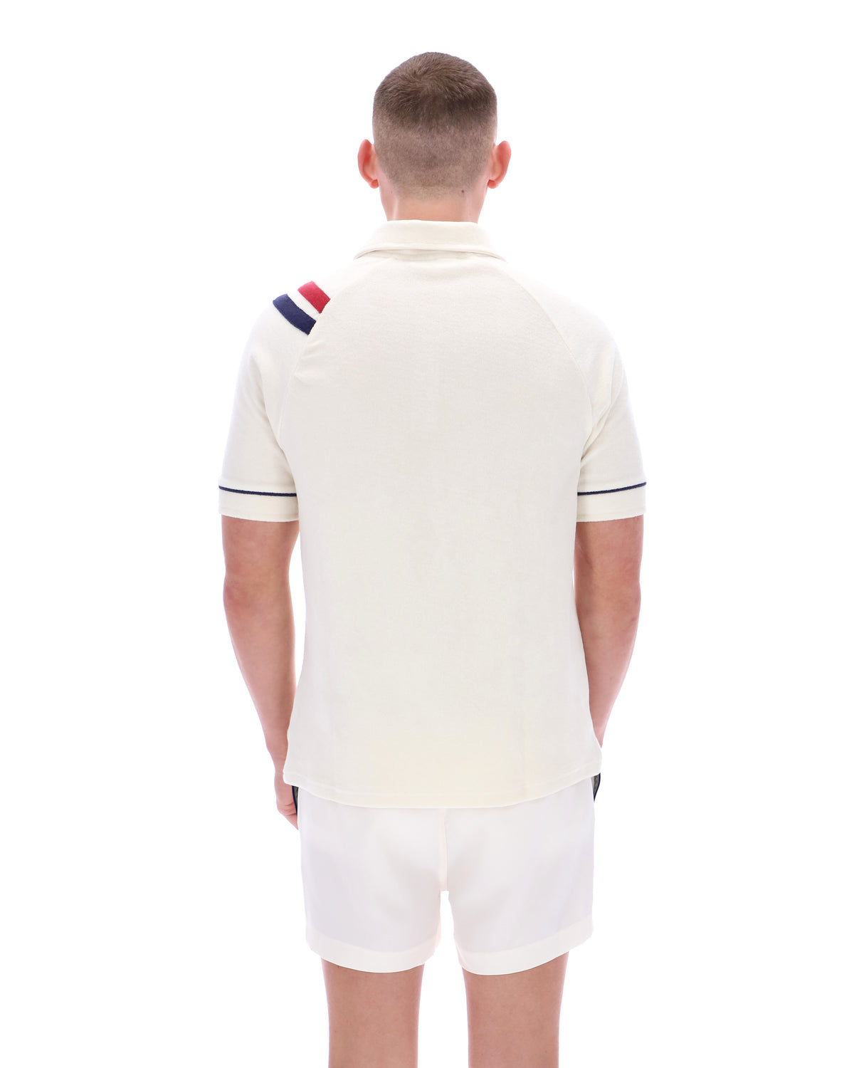 Man wearing a cream polo shirt with a colorful stripe on the sleeve against a white background