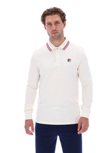 A man wearing a long-sleeve white polo shirt with red and blue striped collar trim and a small Fila logo on the chest, paired with navy pants, against a plain white background.
