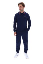A man modeling a navy blue long-sleeve polo shirt and matching jogger pants set by Fila, paired with white sneakers, against a solid white background.