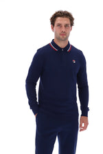 A man wearing a navy blue long-sleeve polo shirt with a red and white striped collar and a small Fila logo on the chest, paired with matching navy pants, against a solid white background.