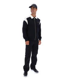 Person wearing a black and white outfit with a cap on a white background