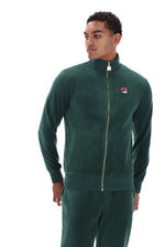 A man wearing a dark green Fila zip-up track jacket and matching track pants, photographed against a plain white background.