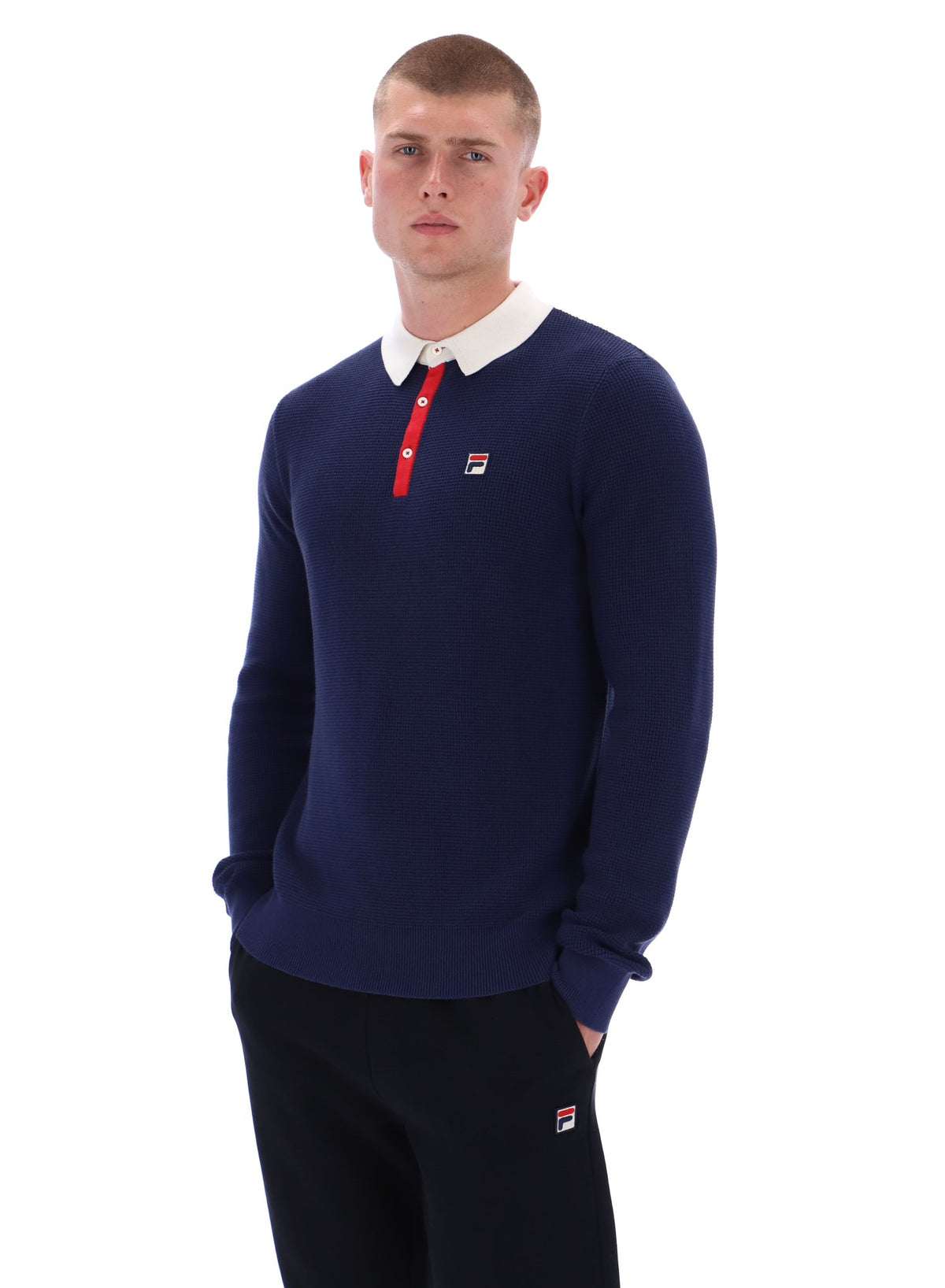Man wearing a navy sweater with a white collar and red accents on a white background
