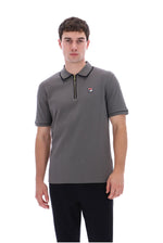 A man wearing a gray short-sleeve polo shirt with a half-zip collar and a small Fila logo on the chest, paired with black pants, against a plain white background.