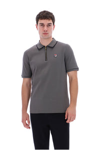 A man wearing a gray short-sleeve polo shirt with a half-zip collar and a small Fila logo on the chest, paired with black pants, against a plain white background.
