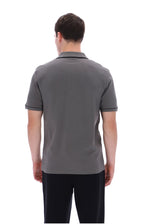 A man viewed from the back wearing a dark gray short-sleeve polo shirt and black pants, standing against a plain white background.