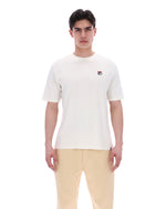 Person wearing a white t-shirt with a small logo on a white background