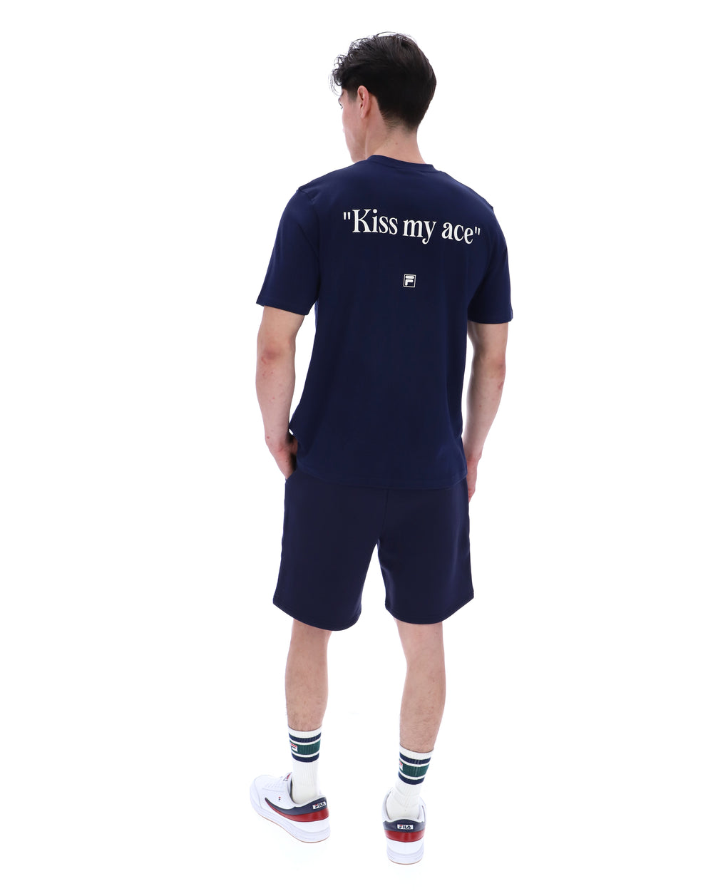 Person wearing a navy blue t-shirt with 'Kiss my ace' text on the back, paired with matching shorts, standing against a white background