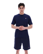 Man wearing a navy blue t-shirt and shorts set with a small FILA logo on a white background