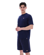 Man wearing a navy blue t-shirt and shorts set with a small FILA logo on a white background