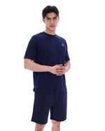 Man wearing a navy blue t-shirt and shorts set with a small FILA logo on a white background