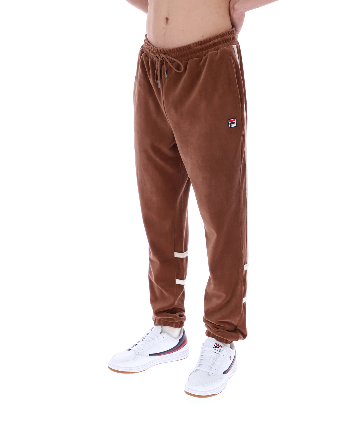 Brown track pants with white stripes worn by a person on a white background