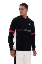 A man modeling a black long-sleeve polo shirt with white side panels, red sleeve stripes, and '1911 Italia' text across the chest, paired with white pants against a white studio background.