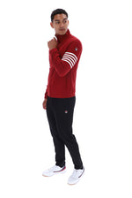 A man modeling a red long-sleeve athletic turtleneck top with white stripes on the sleeve and black sweatpants, standing against a plain white background.