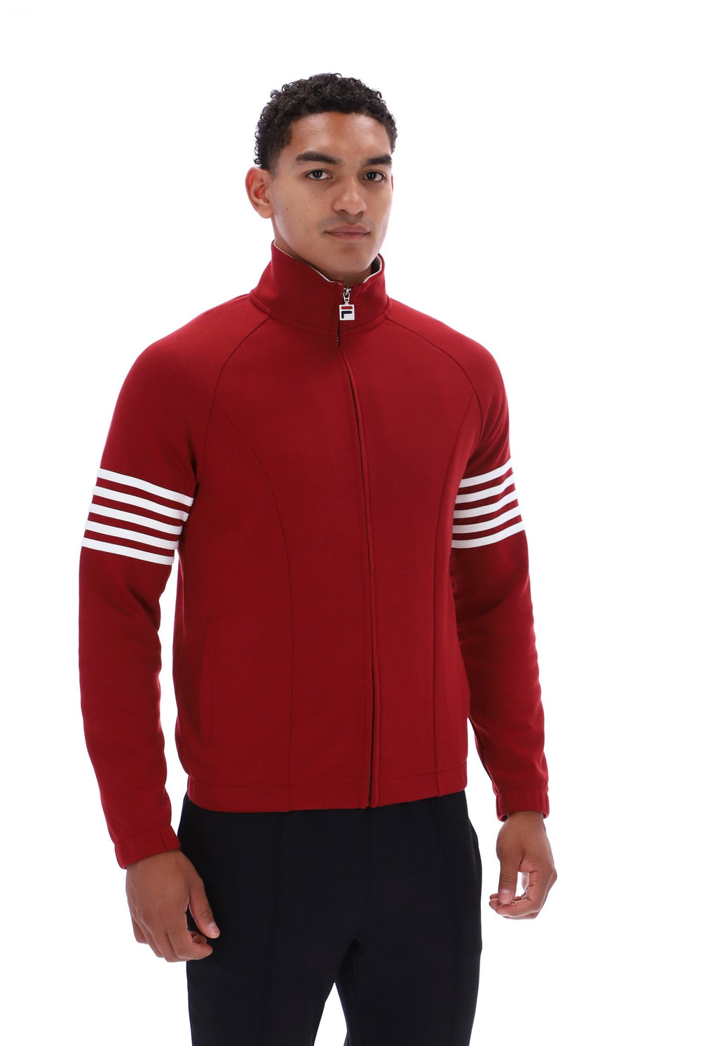 A man wearing a red zip-up athletic jacket with white stripes on the sleeves, paired with black pants, photographed against a solid white background.
