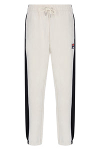 Off-white jogger sweatpants with black side stripes and a small Fila logo patch on the left thigh, featuring an elastic waistband with a drawstring.
