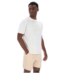 Man wearing a white t-shirt with a cream FILA logo printed on the chest.