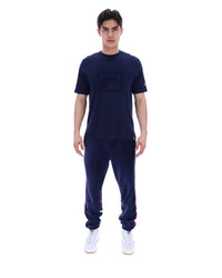 Man wearing a navy blue t-shirt with a FILA logo on the chest and sleeve on a white background