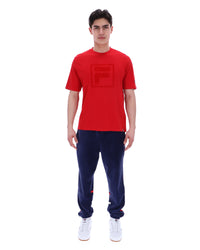 Person wearing a red t-shirt and navy tracksuit on a white background