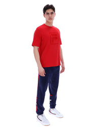Person wearing a red t-shirt and navy tracksuit on a white background