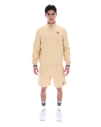 Man wearing a beige quarter zip jumper with a small FILA logo on the chest, paired with matching shorts, against a white background