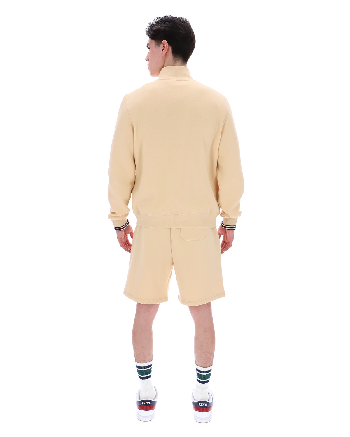 Man wearing a beige quarter zip jumper, paired with matching shorts, against a white background