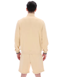Person wearing a beige outfit with shorts on a white background
