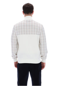 A man viewed from the back wearing a long-sleeve knit sweater with a white and beige plaid upper back and shoulders, a solid white lower back panel, and dark navy pants, against a plain white background.