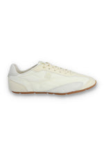 Profile view of a FILA Ritmo trainer in off-white nylon and suede, featuring a low-profile silhouette, tonal laces, an embroidered 'F' logo on the side panel, and a slim brown rubber sole against a white background.