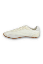 Medial profile view of a FILA Ritmo trainer in off-white nylon, showing the unbranded inner side panel with tonal curved stitching, light grey suede overlays, cream laces, and a slim brown rubber sole against a white background.