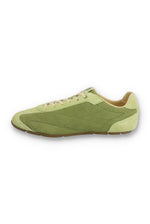 Medial profile view of a FILA Ritmo trainer in green suede, showing the unbranded inner side panel with tonal stitching, contrasting pale green overlays, cream laces, and a slim brown rubber sole against a white background.